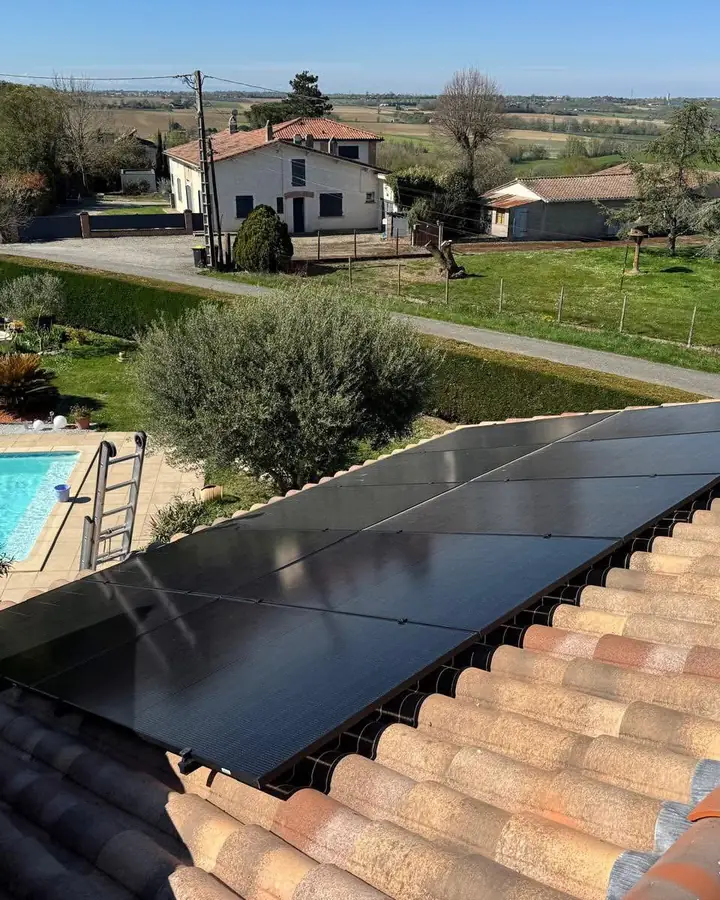 Panneaux solaires noirs posés sur un toit en tuiles canal, piscine en contrebas