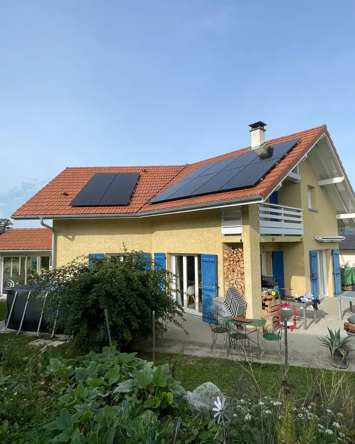 Maison aux volets bleus avec deux rangées de panneaux solaires